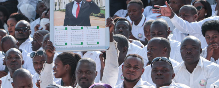 A man holds a calender with the portrait of late Burundi President Pierre Nkurunziza, who died at the age of 55, as people wear white clothes while attending the national funeral at the Ingoma stadium in Gitega, Burundi, on 26 June 2020. Picture: AFP