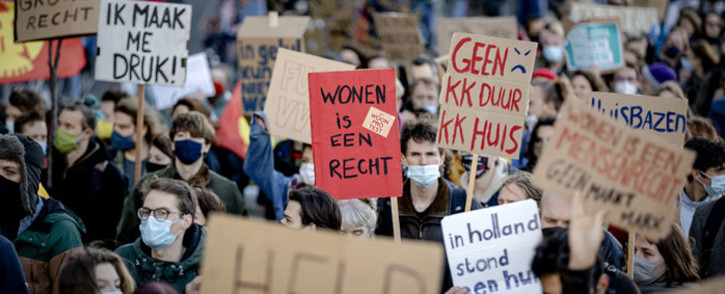 A person holds a placard reading "living is a right" during a protest to demand Dutch government to intervene in the housing market and take measures for more affordable housing in Utrecht on 21 November 2021. Picture: ROBIN VAN LONKHUIJSEN/AFP