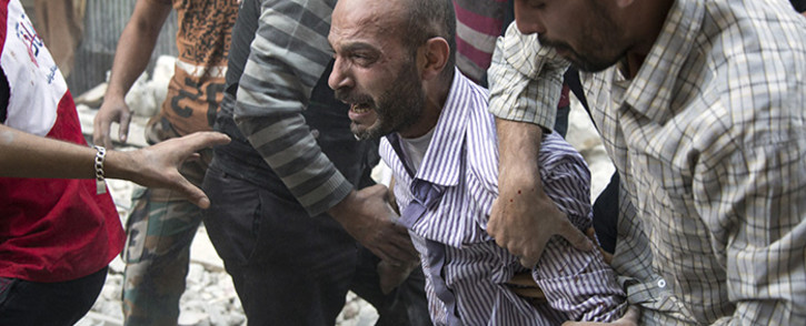 A grief-striken Syrian man is comforted by people as rescuers pull the body of his daughter from the rubble of a building. Picture: AFP.