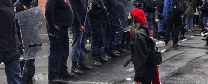 A protester kneels in front of police during an anti-gender-based violence protest in front of Parliament in Cape Town on 29 August 2020. Picture: Courtney Savage