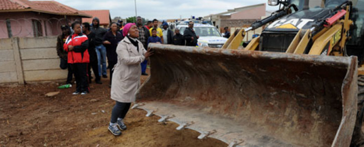 A woman tries to stop a bulldozer from demolishing a house in Lenasia's Extension 13 in southern Johannesburg, on 9 November 2012. Picture: Werner Beukes/SAPA
