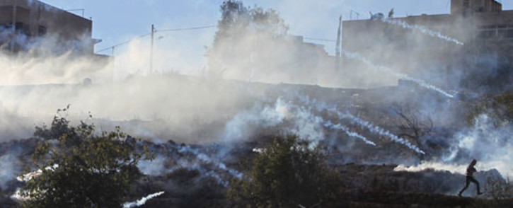 A Palestinian demonstrator runs through a cloud of tear gas during clashes against Israeli forces, outside Ofer, an Israeli military prison near the West Bank city of Ramallah, on November 15, 2012. Picture: AFP.