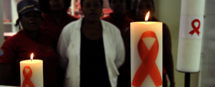 Health workers observing World AIDS Day, posing behind candles commemorating. Picture: AFP.