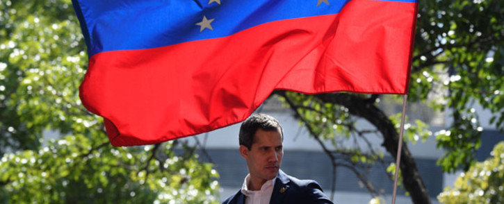 Venezuelan opposition leader and self-proclaimed acting president Juan Guaido is pictured under a national flag during a gathering with supporters after members of the Bolivarian National Guard joined his campaign to oust President Nicolas Maduro, in Caracas on 30 April 2019. Picture: AFP