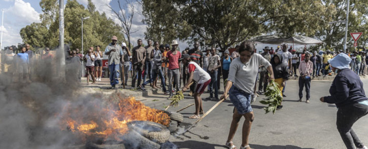 A woman positions a burning tyre as community members protest against the rise of crime in the area in Diepsloot, South Africa, on 6 April 2022. Picture: GUILLEM SARTORIO/AFP