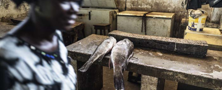 A woman walks past a fish merchant at the Banjul market in Gambia. Picture: AFP.