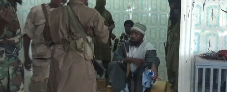 A screengrab from a Boko Haram video shows the movement's leader, Abubakar Shekau (sitting), just before preaching to locals in an unidentified town. Picture: AFP.