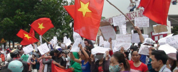 Protesters wave flags and hold placards on a street outside a factory building in Binh Duong on 14 May, 2014, as anti-China protesters set more than a dozen factories on fire in Vietnam. Picture: AFP.