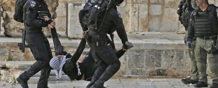 Israeli police carry a wounded young Palestinian demonstrator at Jerusalem's Al-Aqsa mosque compound on 22 April 2022.