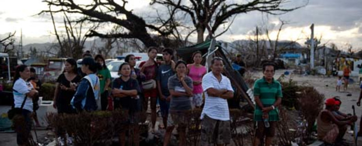 People stand on a corner at the airport watching aid flights land in Tacloban. Picture: AFP. 