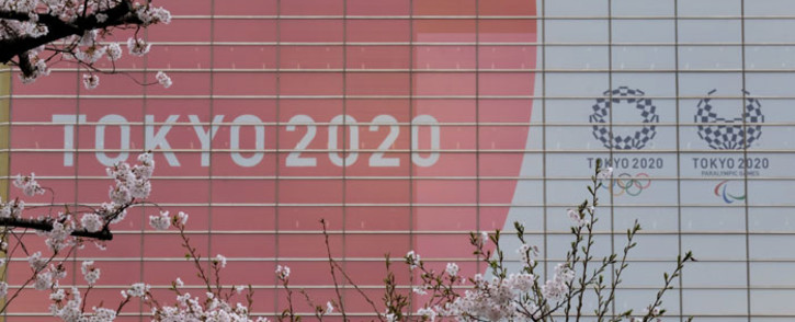 The logo of the Tokyo 2020 Olympic Games and Paralympic Games is displayed behind cherry blossoms in Tokyo on 30 March 2020. Picture: AFP