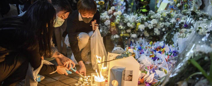 Mourners pay their respects next to flowers and a banner which reads "From all of us - God bless Chow Tsz-Lok" at the site where student Alex Chow, 22, fell during a recent protest in the Tseung Kwan O area on the Kowloon side of Hong Kong on 8 November 2019. Picture: AFP
