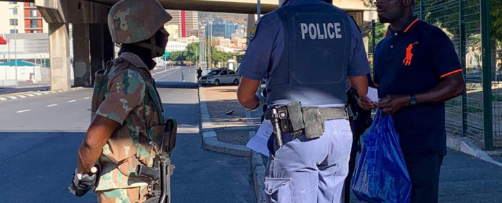 FILE: An SANDF soldier and a police officer check on a member of the public during the lockdown in Woodstock, Cape Town on 27 March 2020. Picture: Kaylynn Palm/EWN