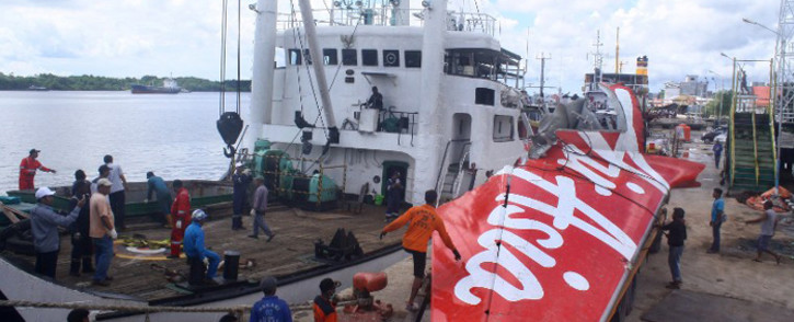 Workers load the tail of AirAsia flight QZ8501 onto a truck at Kumai sea port, in Central Kalimantan, on 7 February, 2015 before they transport it to Jakarta. Picture: AFP
