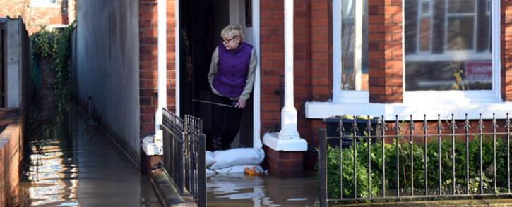 A woman looks out from a flooded property adjacent to the River Foss which burst its banks in York, northern England, on 27 December, 2015. Picture: AFP.