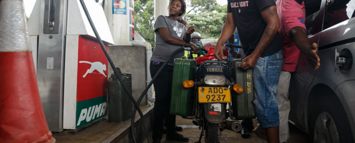 FILE: A petrol attendant serves a motorcyclist with two jerry cans attached to his motorbike at a fuel station, on 11 January 2019 in Harare, Zimbabwe. Motorists are spending nights waiting in long queues for petrol and diesel as the country is experiencing crippling fuel shortages. Picture: AFP