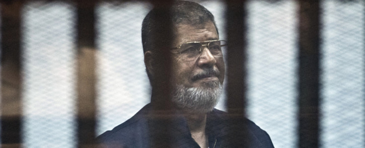 File: Egypt's ousted Islamist president Mohamed Morsi stands behind the bars during his trial in Cairo on 16 June, 2015. Picture: AFP.