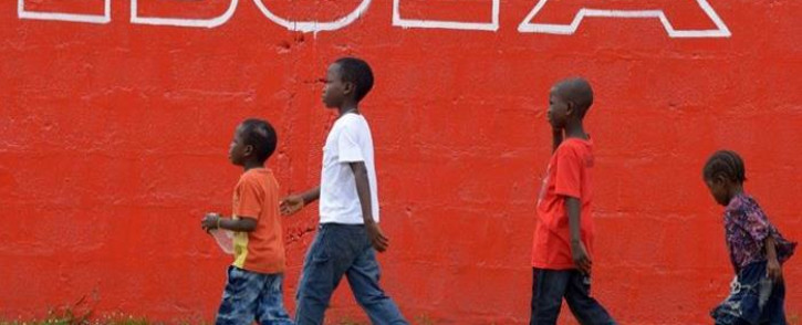 FILE: A file photo taken on 31 August, 2014 shows children walking past a slogan painted on a wall reading 'Ebola' in Monrovia. Picture: AFP.