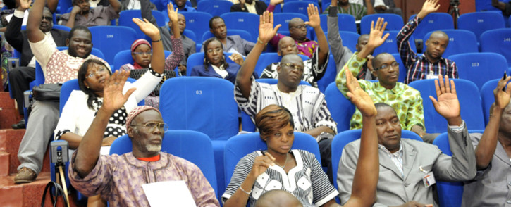Members of Burkina Fasoâs interim parliament raise their hands on 16 July, 2015 in Ouagadougou as they vote on a resolution asking the High Court to put deposed leader Blaise Compaore on trial for high treason and violating the constitution. Picture: AFP.