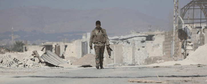 A member of Syria's pro-government forces walks past damaged structures in the town of Mudyara, formerly held by opposition groups, in the centre of the eastern Ghouta region as regime troops carry on with their assault on the rebel-held enclave, just outside the capital Damascus. Picture: AFP