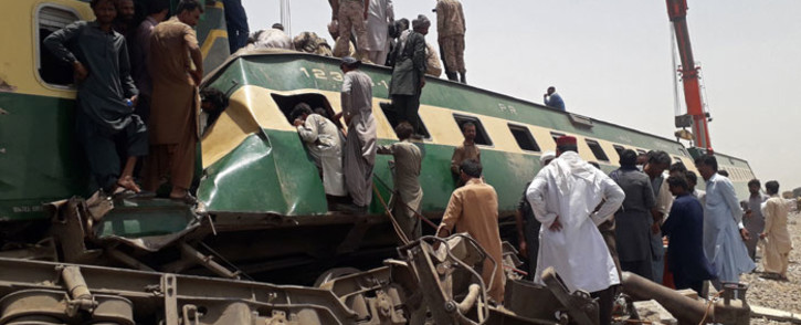 Security personnel and onlookers stand at the site of a train accident in Daharki area of the northern Sindh province on 7 June 2021, as at least 34 people were killed and dozens injured when a packed Pakistani inter-city train ploughed into another express that had derailed earlier, officials said. Picture: Shahid Ali/AFP