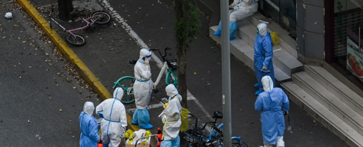 Health workers wearing personal protective equipment (PPE) stand next to the entrance of a neighborhood during a COVID-19 lockdown in the Jing'an district in Shanghai on 12 April 2022. Picture: HECTOR RETAMAL/AFP