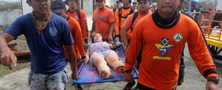 Rescue workers carry a woman about to give birth at a makeshift Department of Health medical center at the Tacloban airport in the aftermath of Super Typhoon Haiyan in Tacloban, eastern island of Leyte on November 9, 2013. Picture: AFP.