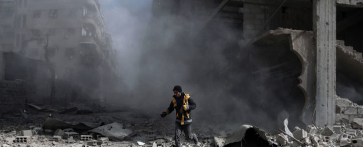 FILE: A civil defence volunteer, known as the White Helmets, checks the site of a regime air strike in the rebel-held town of Saqba, in the besieged Eastern Ghouta region. Picture: AFP.
