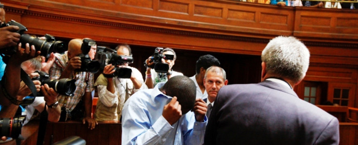 Zola Tongo (C) covers his face as he lead up from the holding cells to attend a session at the Cape Town High Court, Cape Town, South 07 December 2010. EPA/NIC BOTHMA
