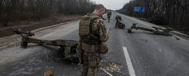 This handout photograph released by the General Staff of the Armed Forces of Ukraine on 27 March 2022, shows Ukrainian soldiers walking among destroyed Russian military equipment following a battle in the town of Trostyanets, Sumy region.