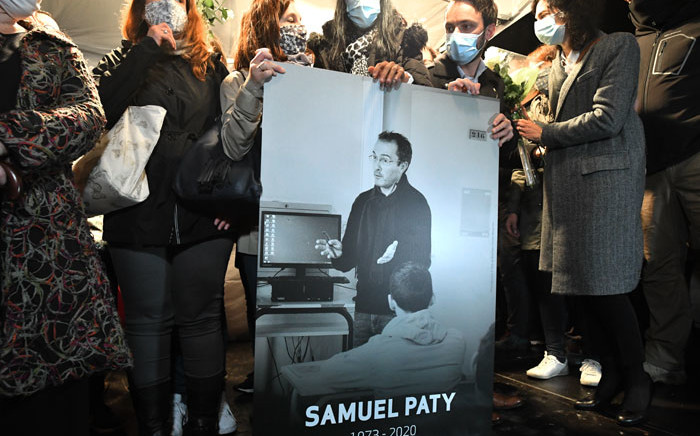 Relatives and colleagues hold a picture of Samuel Paty during the 'Marche Blanche' in Conflans-Sainte-Honorine, northwest of Paris, on 20 October 2020, in solidarity after he was beheaded for showing pupils cartoons of the Prophet Muhammad. Picture: AFP