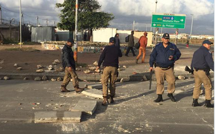 Officers clearing the road of the stones that were thrown by protestors. Picture: Masa Kekana/EWN