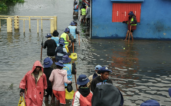 People walk through flood water after several houses were affected by rising water following heavy rains in 67 Hectares neighbourhood in Antananarivo, capital of Madagascar, on January 24, 2022. Antananarivo and several regions of Madagascar have been hit by strong tropical storms that have left over 30 people dead and more than 62,000 people affected, according to the authorities. Picture: RIJASOLO / AFP