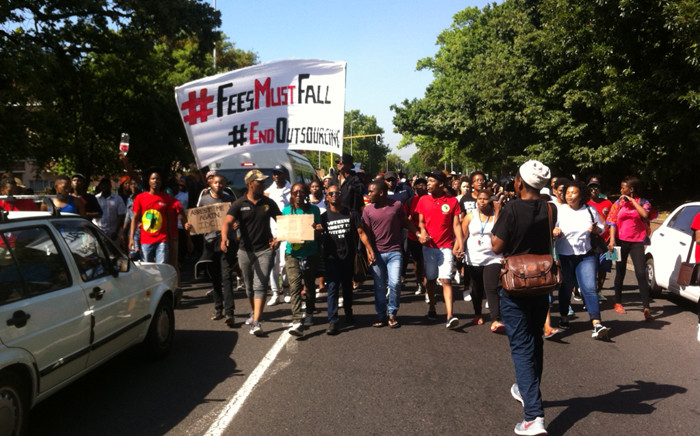 Protesters walk along main road, halting traffic briefly before turning up to lower campus again. Police presence remains. Picture: Anthony Molyneaux/EWN.