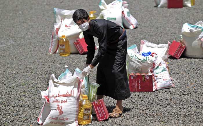 FILE: A Yemeni youth carries a portion of food aid, distributed by Yadon Tabney development foundation, in Yemen's capital Sanaa on 17 May 2020. Picture: AFP.