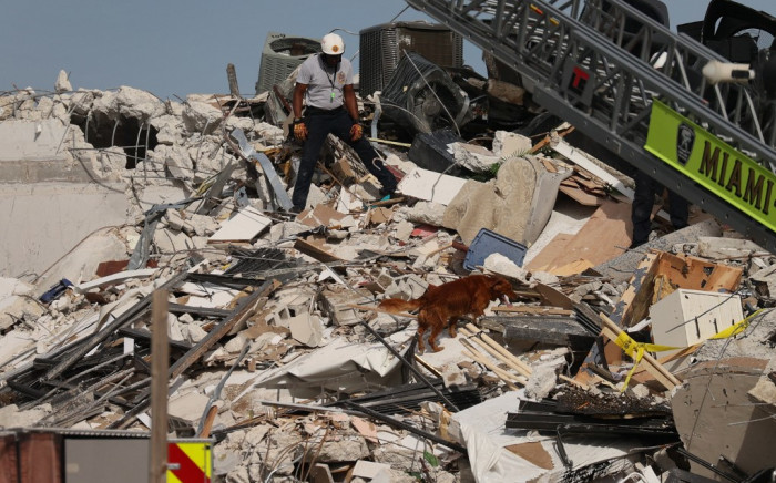 A Miami-Dade Fire Rescue person and a K-9 continue the search and rescue operations in the partially collapsed 12-story Champlain Towers South condo building on 24 June 2021 in Surfside, Florida. Picture: JOE RAEDLE/AFP