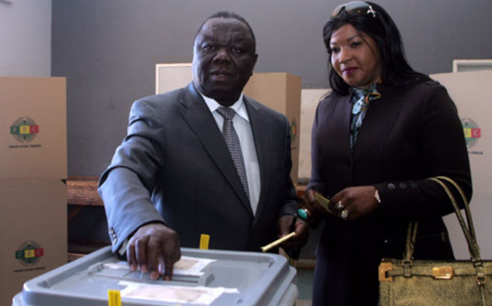 Zimbabwe's Prime minister, leader and candidate of the MDC, Morgan Tsvangirai, flanked by his wife Elizabeth, casts his ballot in a polling station in Harare. Picture: AFP.