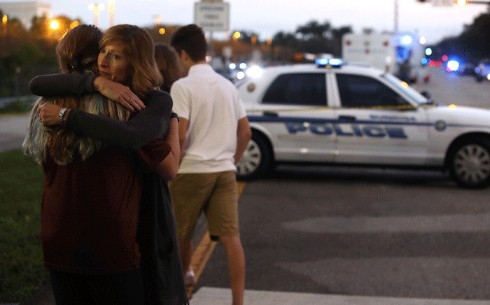 FILE: Kristi Gilroy hugs a young woman at a police checkpoint near the Marjory Stoneman Douglas High School where 17 people were killed by a gunman on 15 February 2018 in Parkland, Florida. Picture: AFP.