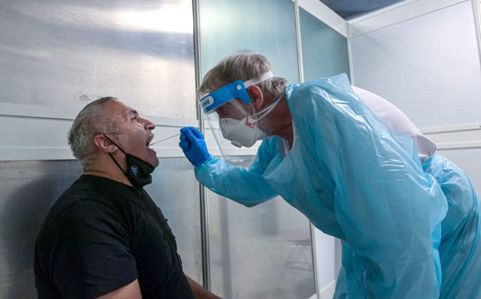 FILE: A passenger is tested by a doctor at a coronavirus screening station in the medical center of the airport in Duesseldorf, western Germany, on 27 July 2020. Picture: AFP