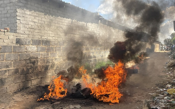 Tyres burn just meters from the police station on 6 April 2022 as Diepsloot residents protest over crime in the area. Picture: Masechaba Sefularo/Eyewitness News