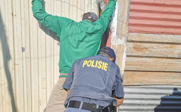 Police search a resident as part of Operation Okae Molao in the Slovo Park informal settlement, west of Johannesburg on 14 May 2020. Picture: @GP_CommSafety/Twitter