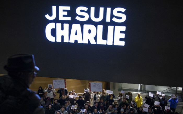 People hold signs with words reading “Je Suis Charlie” (I Am Charlie) beneath an electronic display echoing the sentiment outside the Newseum 7 January, 2015 in Washington. Picture: AFP 