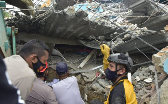 Rescuers search for survivors at the Mitra Manakarra hospital in Mamuju city on  15 January 2021, where patients and staff were trapped beneath the rubble after the hospital was flattened when a 6.2-magnitude earthquake rocked Indonesia's Sulawesi island. Picture: Firdaus/AFP.