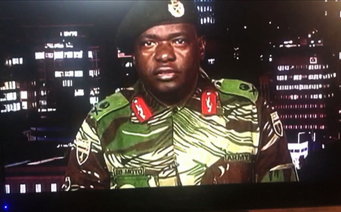 This screengrab taken early on 15 November 2017 from a television broadcast on the Zimbabwe Broadcasting Corporation (ZBC) shows Zimbabwe Major General Sibusiso Moyo reading a statement at the ZBC broadcast studio in Harare. Picture: AFP.