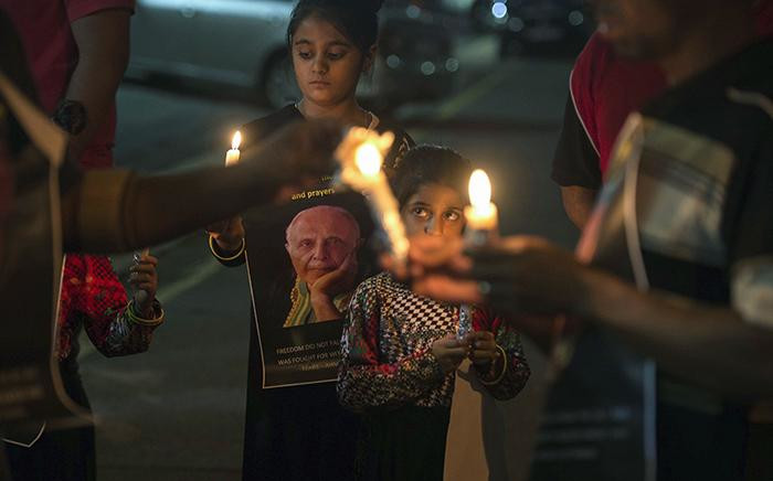 People hold candles as they gather for a night vigil to pray for Anti Apartheid struggle veteran and Rivonia trialist Ahmed Kathrada currently ill in hospital, on March 16, 2017 in Johannesburg, South Africa. Picture: AFP