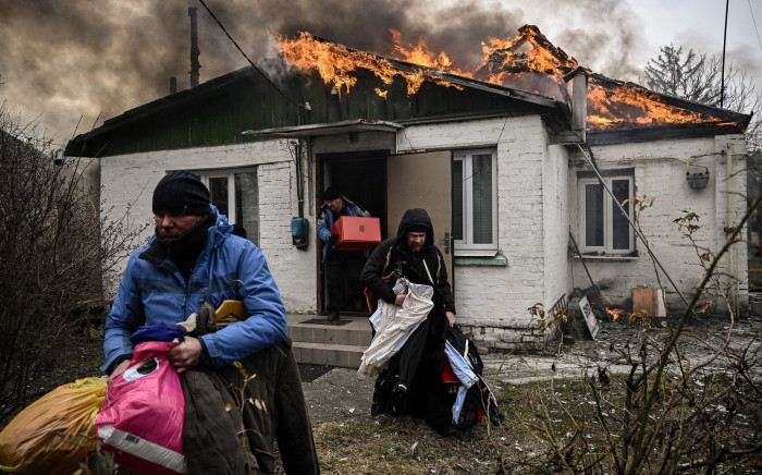 People remove personal belongings from a burning house after being shelled in the city of Irpin on 4 March 2022.