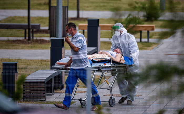 Medics escort a woman into a hospital where patients infected with the COVID-19 novel coronavirus are being treated in the settlement of Kommunarka outside Moscow, Russia, on 30 June 2021. Picture: Dimitar DILKOFF/AFP