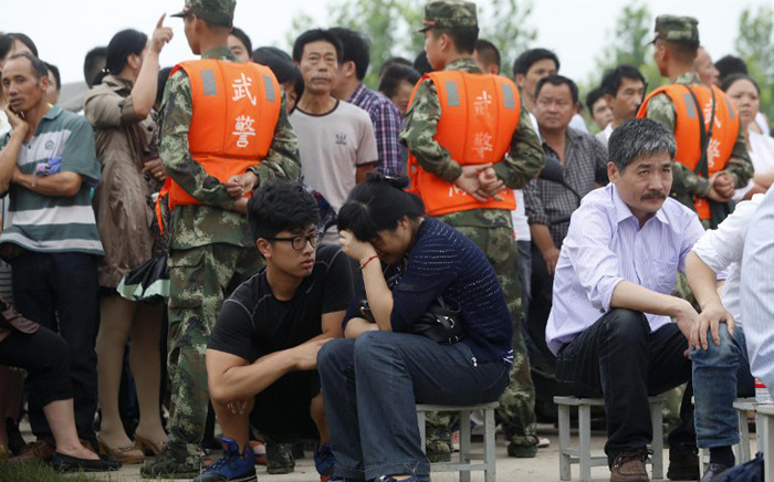 This photo taken on 3 June, 2015 shows a relative (centre R) of a passenger - missing after a Chinese cruise ship capsized on the Yangtze river - wiping away tears as relatives gather at the disaster site in Jianli, in central China's Hubei province. Picture: AFP.