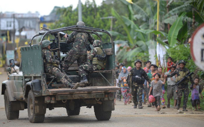Philippine troops escort rescued civilians while a military truck covers them from sniper fire at a village on the outskirts of Marawi on the southern island of Mindanao. Picture: AFP