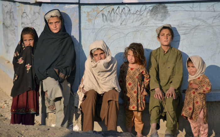 Children bask in the sun next to a wall along a street in Nad Ali district, Helmand province on 10 November 2021. Picture: AFP